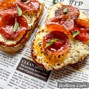 Two slices of toasted bread topped with creamy cheese, pepperoni slices, and small green herb leaves, served on a newspaper-themed paper.