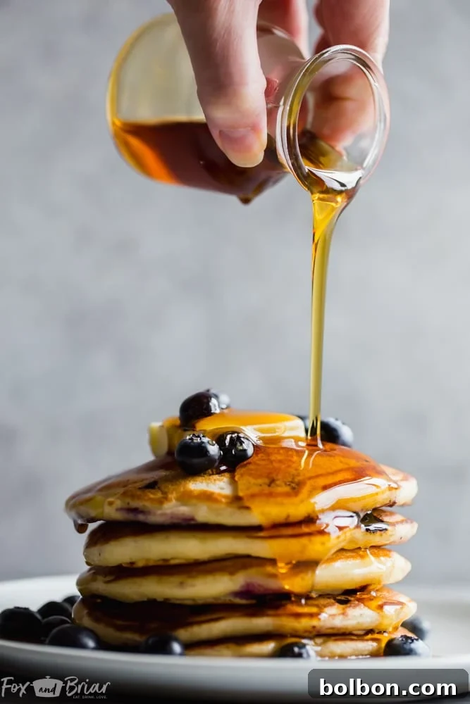 Berry Burst Buttermilk Pancakes 2 Stack of fluffy buttermilk blueberry pancakes topped with fresh blueberries and maple syrup