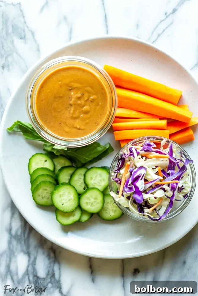 A beautifully presented bowl of creamy Thai peanut sauce, garnished with fresh cilantro and a lime wedge, ready to be served as a versatile dipping sauce for various dishes.