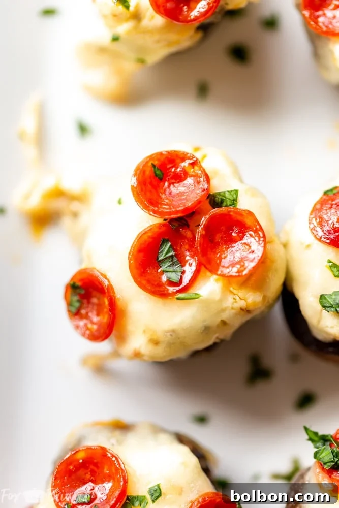 Cheesy Pizza Stuffed Mushrooms 7 A vibrant, well-lit shot of a serving of Pizza Dip Stuffed Mushrooms on a white plate, ready to be enjoyed.