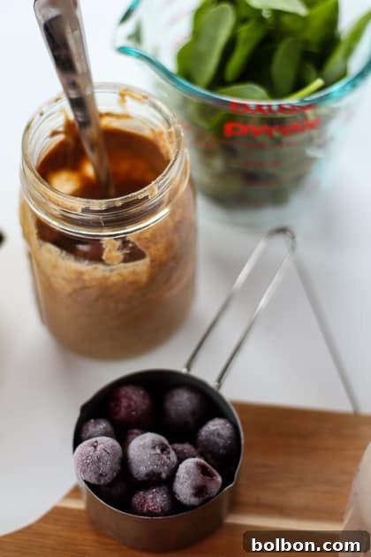 Closeup of Cherry Almond Green Smoothie in a glass, vibrant purple hue.