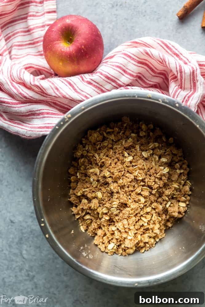 A freshly baked apple crisp, warm and bubbling, served in a ceramic baking dish with a scoop missing, hinting at its deliciousness.