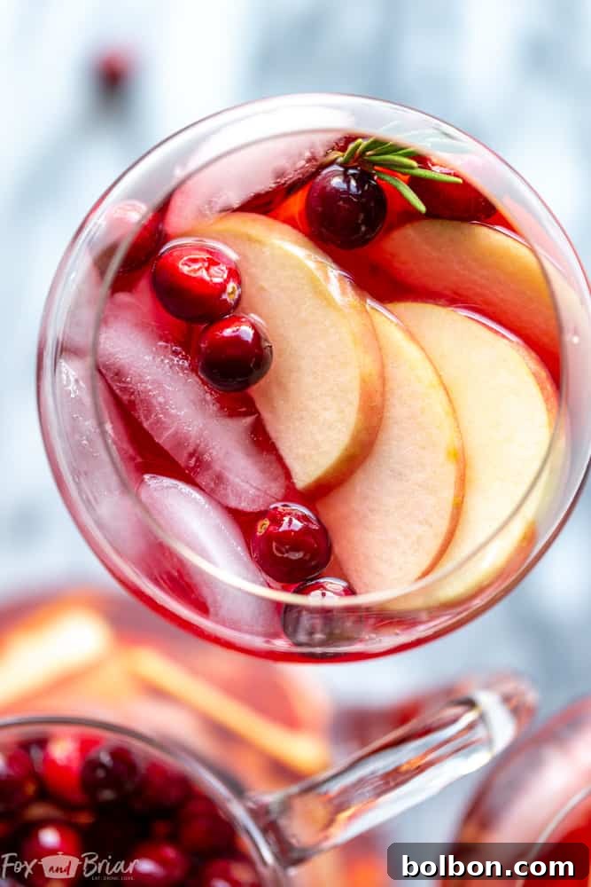 Full pitcher of Cranberry Orange Sangria with glasses and garnishes