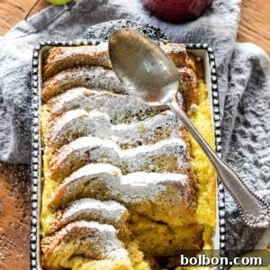 A square baking dish filled with golden-brown Apple Cardamom Bread Pudding