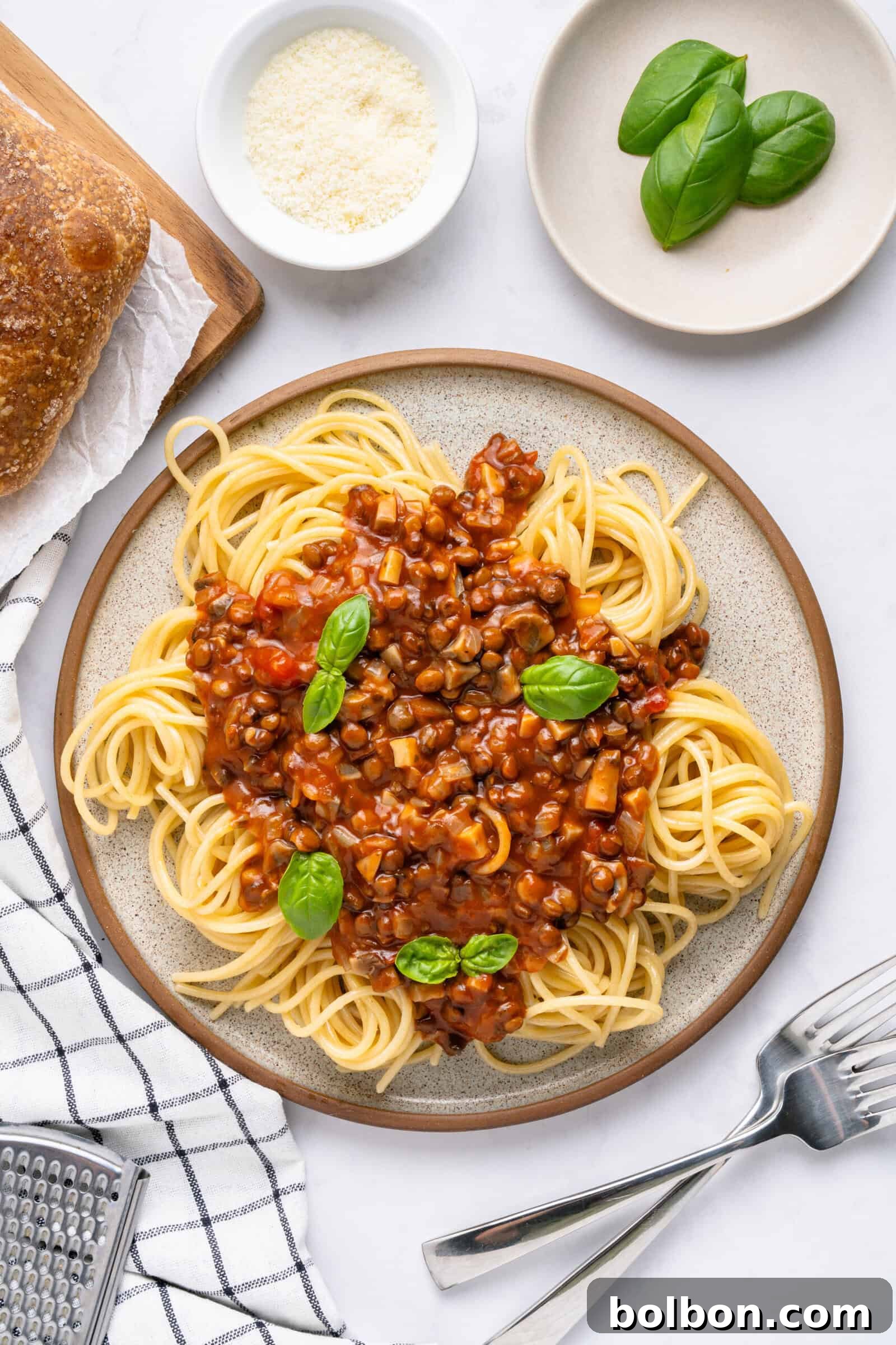 A beautifully plated dish of spaghetti topped with a rich, red lentil bolognese sauce and fresh basil leaves, evoking warmth and comfort.