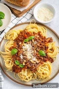 A plate of spaghetti with Lentil Bolognese, topped with fresh basil, ready to eat.