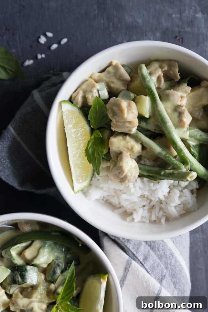 A vibrant bowl of Thai Green Curry with Chicken, garnished with fresh basil leaves and a lime wedge, ready to be served over rice.