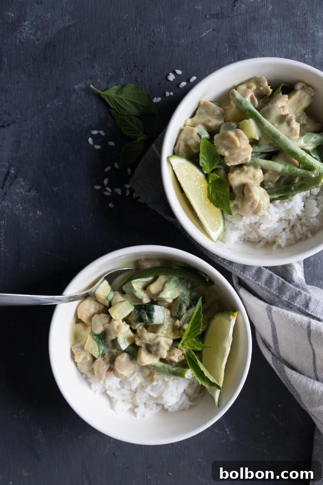 A close-up shot of the finished Thai Green Curry with Chicken, showcasing its vibrant green color, creamy texture, and the fresh Thai basil leaves on top, served in a rustic bowl.