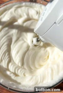 Protein Packed Pancake Bites 6 A close-up of an electric hand mixer whipping a creamy, white mixture in a glass bowl, creating smooth, fluffy peaks.