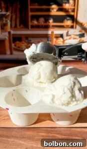 Protein Packed Pancake Bites 8 An ice cream scooper is serving two scoops of vanilla ice cream into a white tray with sprinkle designs, with a bakery display blurred in the background.
