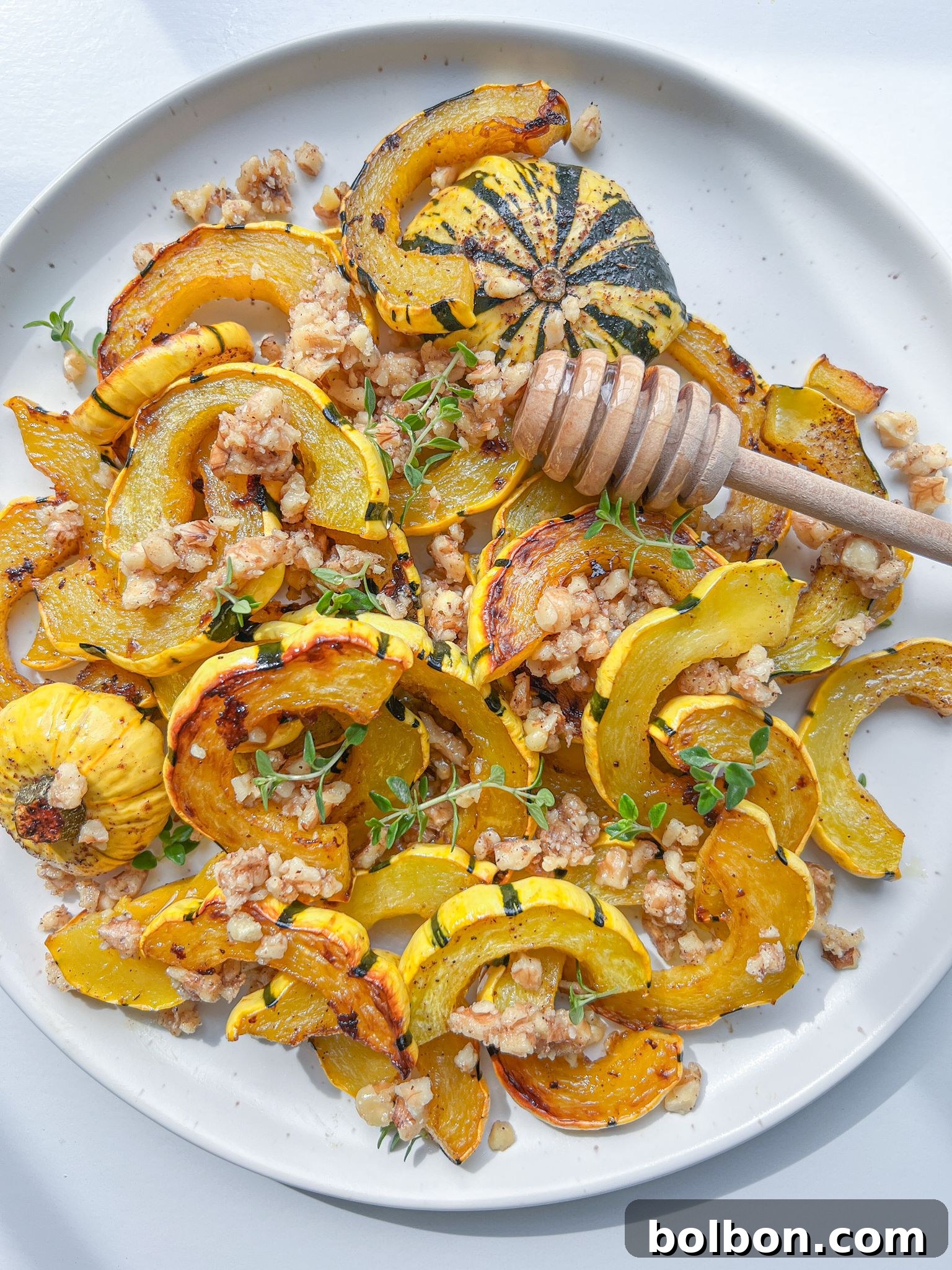 Sweet and Savory Delicata Roast 2 Beautifully roasted delicata squash slices, golden brown and caramelized, artfully arranged on a serving plate. The dish is generously topped with a rich honey-walnut mixture and garnished with fresh thyme sprigs, showcasing a perfect balance of sweet and savory flavors for a delightful fall meal.