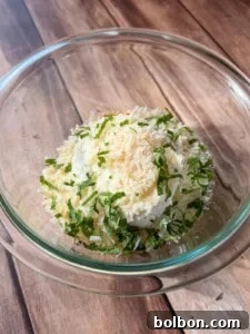 Layered Cabbage Comfort 11 A glass bowl filled with ricotta cheese, grated parmesan, and chopped fresh basil, sitting on a wooden surface.