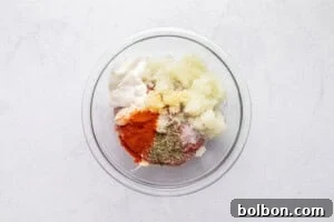 Mixing ground meat with spices and yogurt in a bowl.