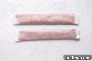 Rolled doner kebab meat in parchment paper on a baking sheet.