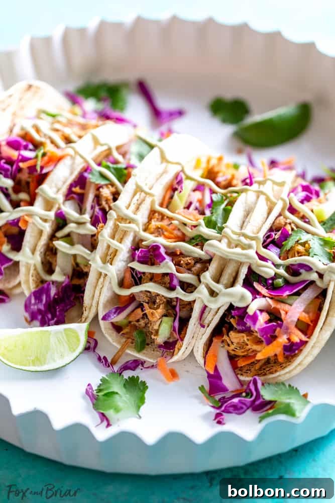 Assembled Pulled Pork Tacos A beautifully assembled Slow Cooker Mexican Pulled Pork Taco with cilantro lime slaw and avocado crema on a warm tortilla, ready to be enjoyed.