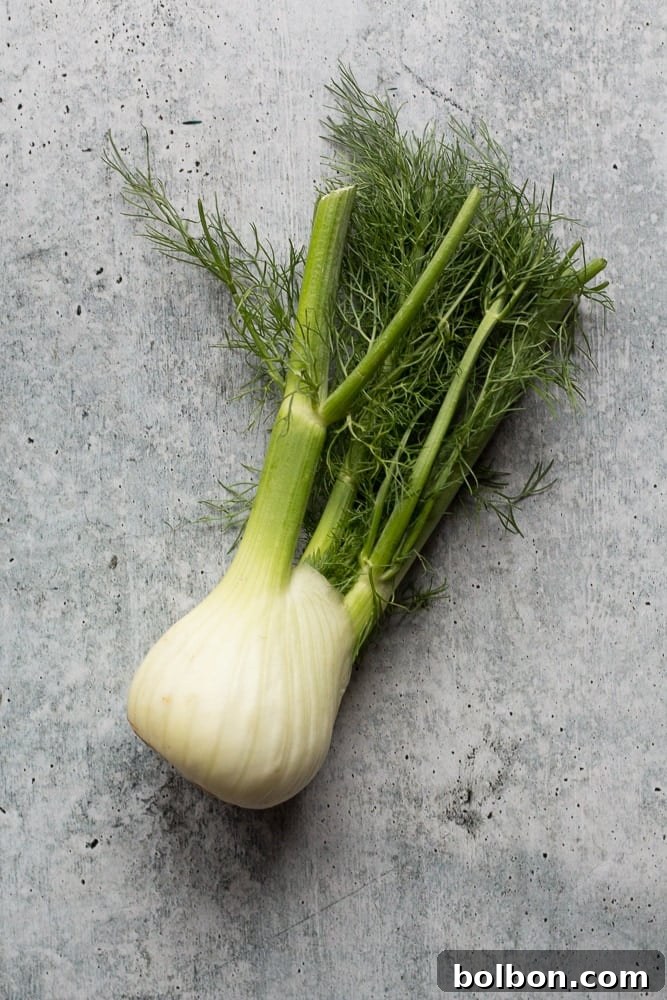 Image showing a red onion and a fennel bulb thinly sliced on a cutting board, ready to be cooked for the breakfast casserole.