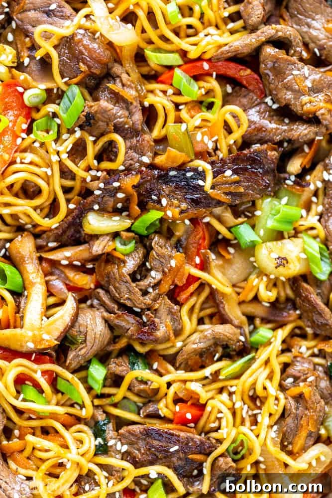 Ingredients for Beef Ramen Noodle Stir Fry laid out on a cutting board, including thinly sliced beef, vibrant vegetables, and prepared ramen noodles.