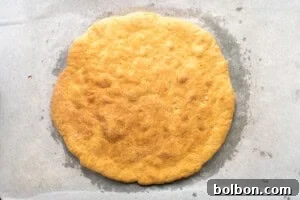 Pre-baked pizza crust on a baking sheet, lightly golden.