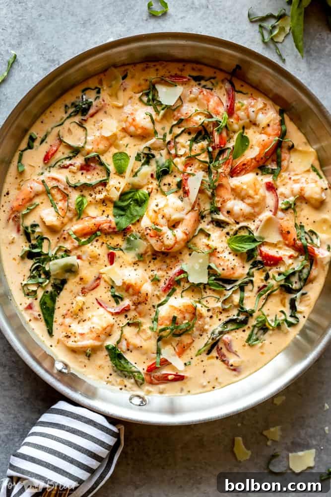 A close-up of a skillet filled with Creamy Parmesan Basil Shrimp, showing the cooking process and rich sauce.