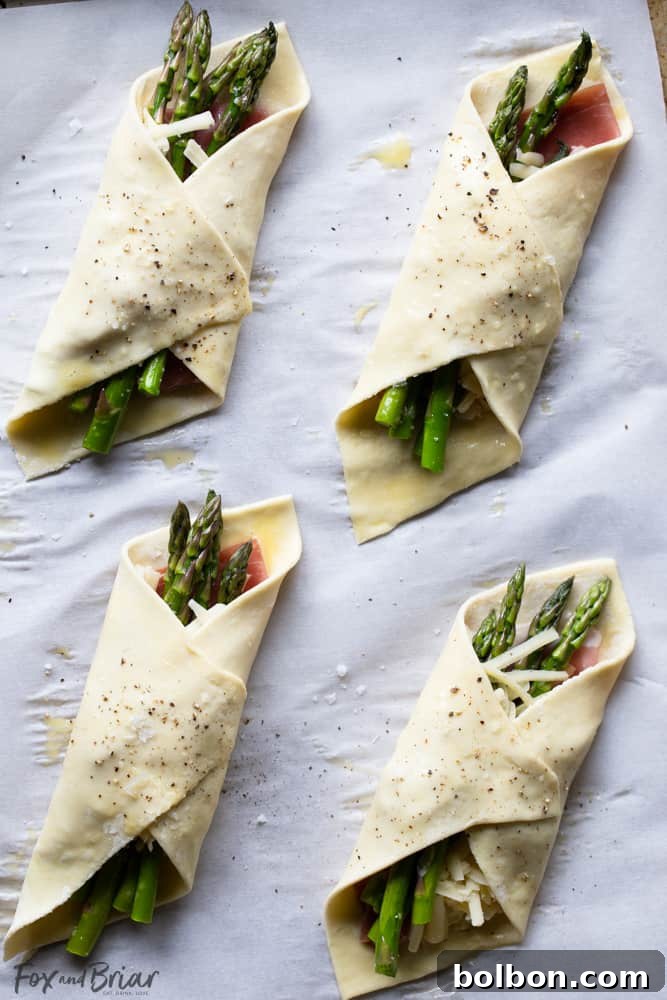 Raw Prosciutto Asparagus Puff Pastry Bundles ready for the oven, showing the neatly folded pastry around the filling.