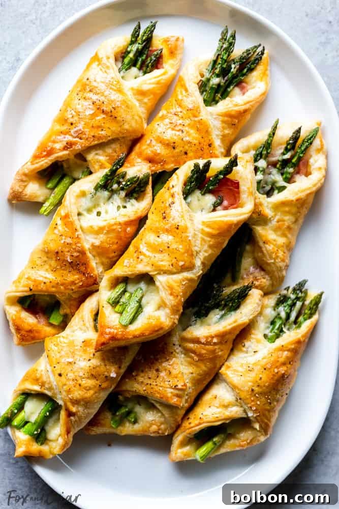 Individual Prosciutto Asparagus Puff Pastry Bundles cooling on a wire rack after baking.