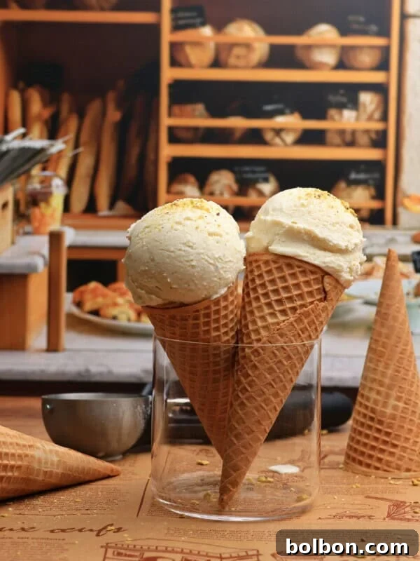 Two waffle cones filled with Viral Snow Ice Cream stand upright in a glass jar on a wooden table, with a bakery display of bread and pastries in the background.