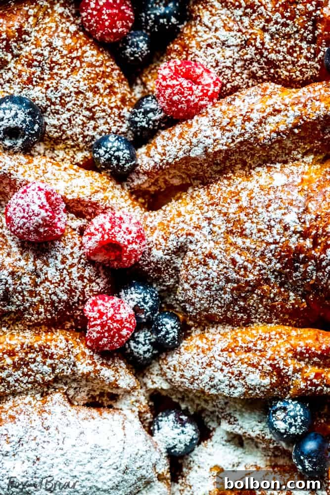Close up of Overnight Croissant French Toast Bake with fresh blueberries and raspberries, ready to be served