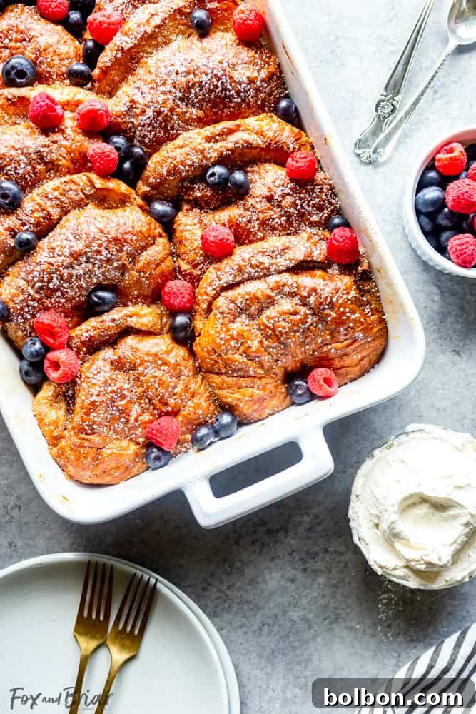 Overnight Croissant French Toast Strata 3 Overnight Croissant French Toast Bake, a full pan ready for serving with powdered sugar and fresh berries