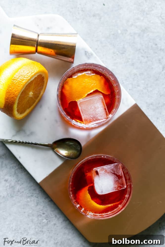 Two vibrant red Negroni cocktails expertly garnished with fresh orange slices, seen from an overhead view.