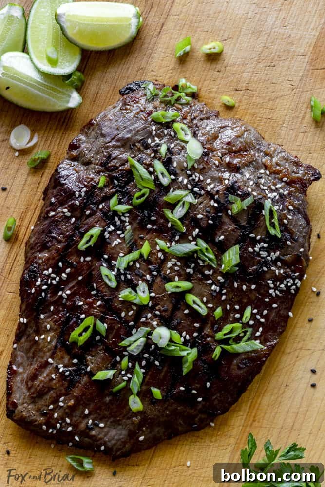 Grilled flank steak garnished with sesame seeds and chopped green onions on a platter, ready to serve.