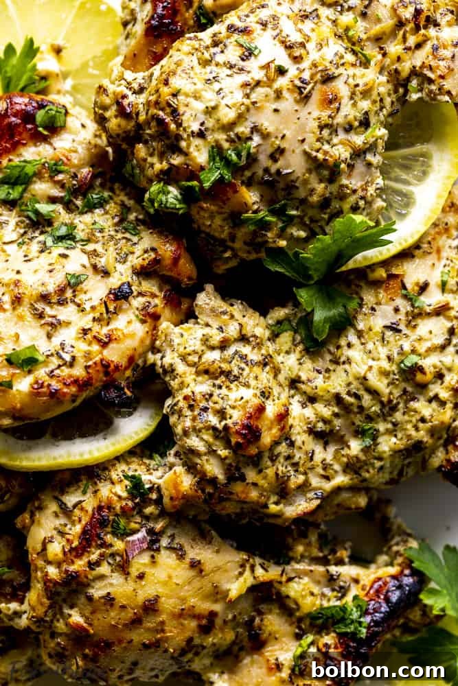 A delicious close-up of a serving of Oven Baked Greek Chicken Thighs, showing the juicy interior and browned exterior, garnished with fresh herbs.