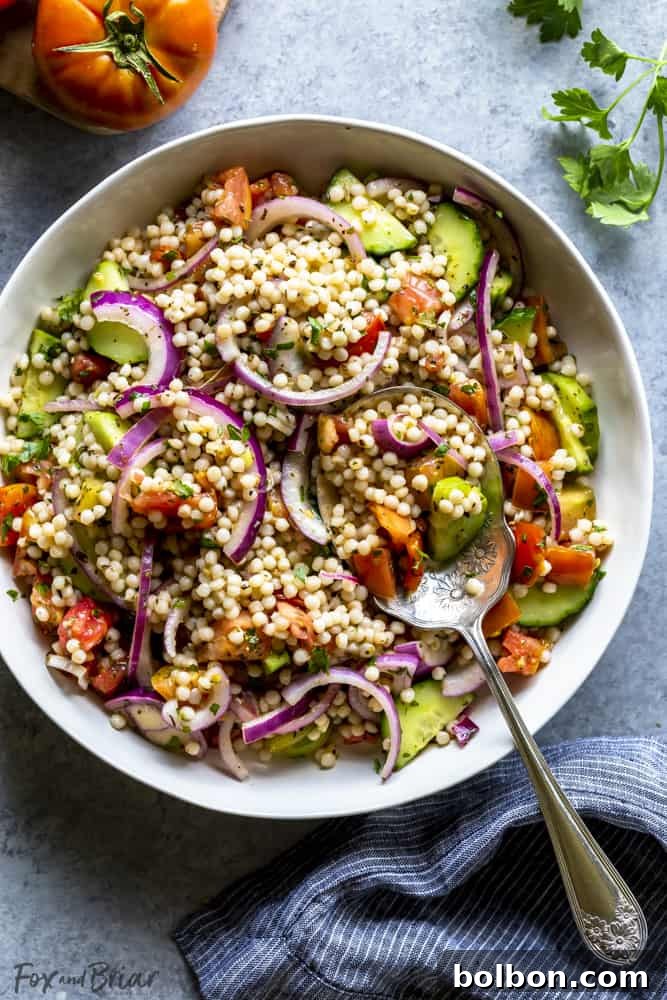 Fresh Israeli Couscous Salad: A light, healthy, and easy Mediterranean pearl couscous recipe perfect for summer potlucks, BBQs, and picnics. Vibrant Israeli couscous salad with fresh vegetables in a white bowl, ready to be served