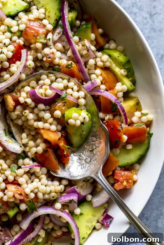 Mediterranean Couscous Salad: A refreshing, cold side dish with giant couscous, fresh herbs, and a lemon-herb dressing for BBQs and picnics. Close-up of pearl couscous salad featuring diced cucumbers, tomatoes, and red onion, tossed with herbs and dressing