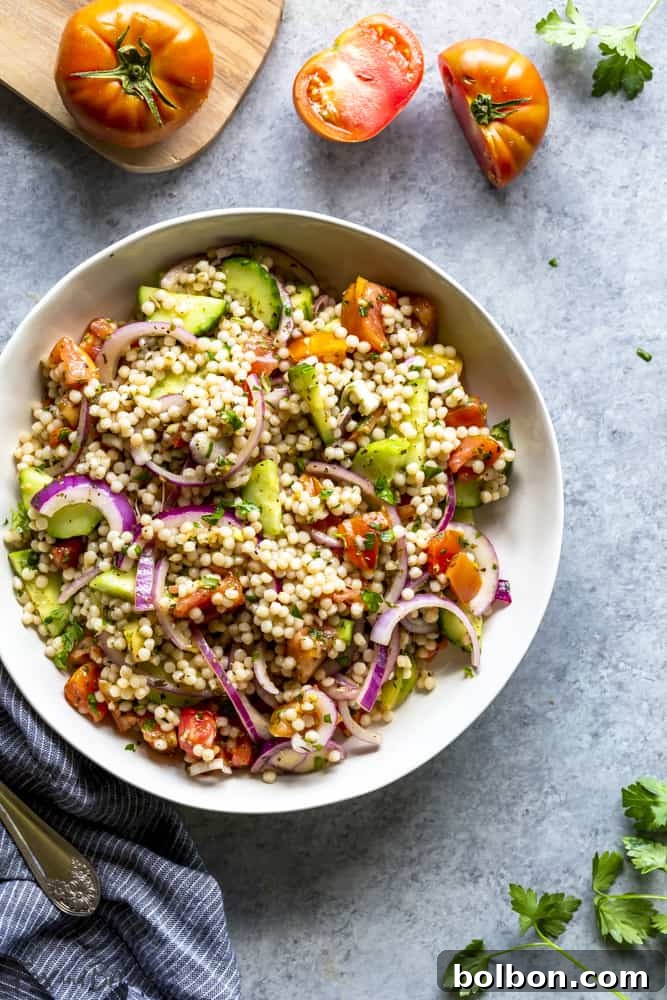 Vegan Couscous Salad: An easy, healthy, and cold Middle Eastern side dish with giant couscous, ideal for summer picnics and BBQs. Close-up of a healthy vegan couscous salad with vibrant heirloom tomatoes, demonstrating its fresh appeal