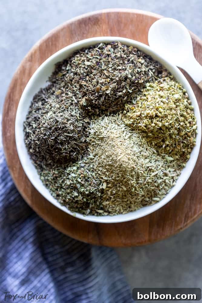 Freshly prepared homemade Italian seasoning blend in a clear glass jar on a rustic wooden surface, highlighting its vibrant green color.