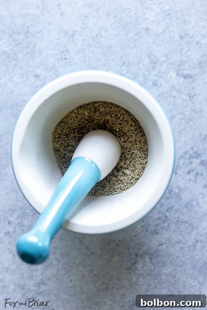 A selection of dried herbs including oregano, basil, and thyme, meticulously arranged on a light-colored surface, ready to be blended into Italian seasoning.
