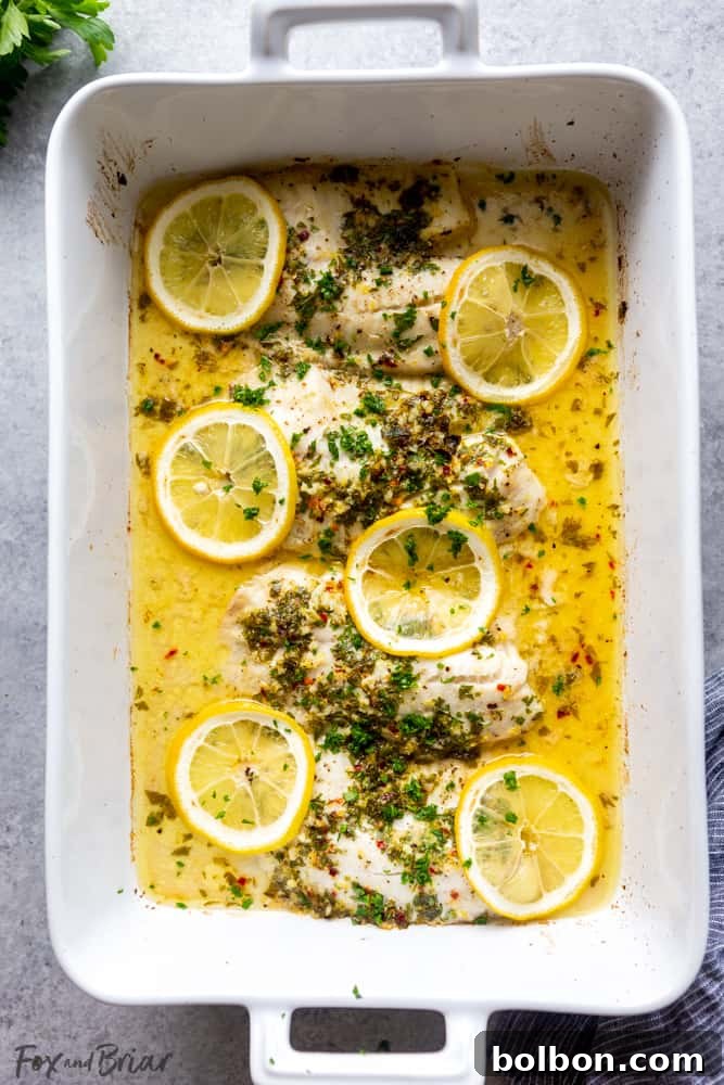 Tilapia fillets seasoned with salt, pepper, lemon slices, and fresh parsley in a baking dish