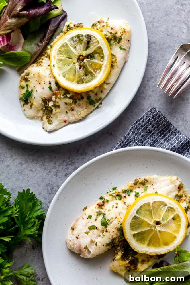 Close-up of baked lemon butter tilapia, garnished with fresh parsley and lemon slices