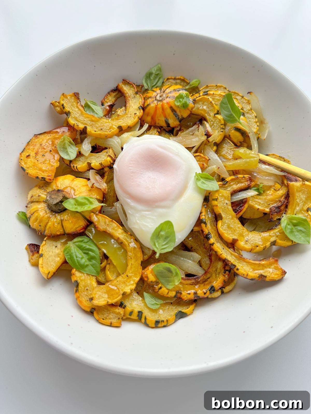 Roasted delicata half-moons with onions & cubanelle, topped with a poached egg and fresh herbs, presented in an elegant setting.