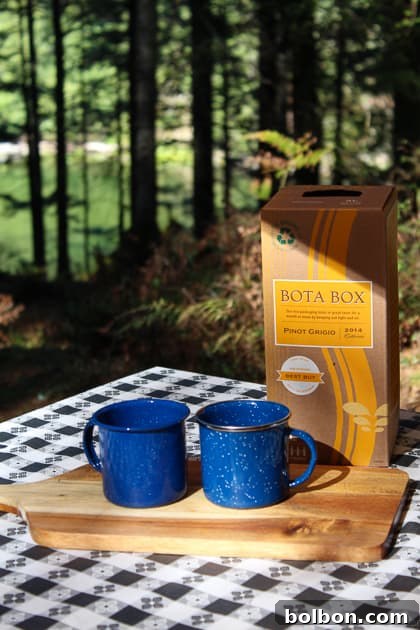 Outdoor glamping setup with a portable happy hour spread, including cheese, wine, and mugs