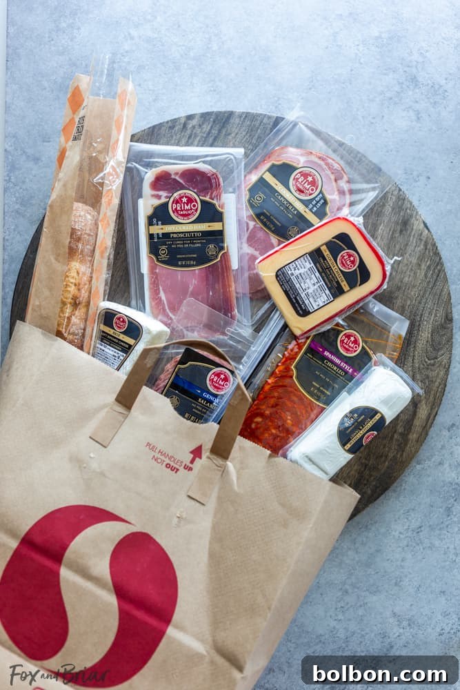 An overhead shot of a charcuterie board with various cheeses, cured meats, crackers, and fresh summer fruits, highlighting the selection from Safeway.