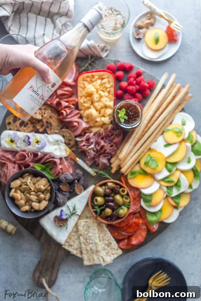 The fully garnished summer charcuterie board, complete with fresh herbs and edible flowers, showcasing a beautiful, abundant spread for guests.