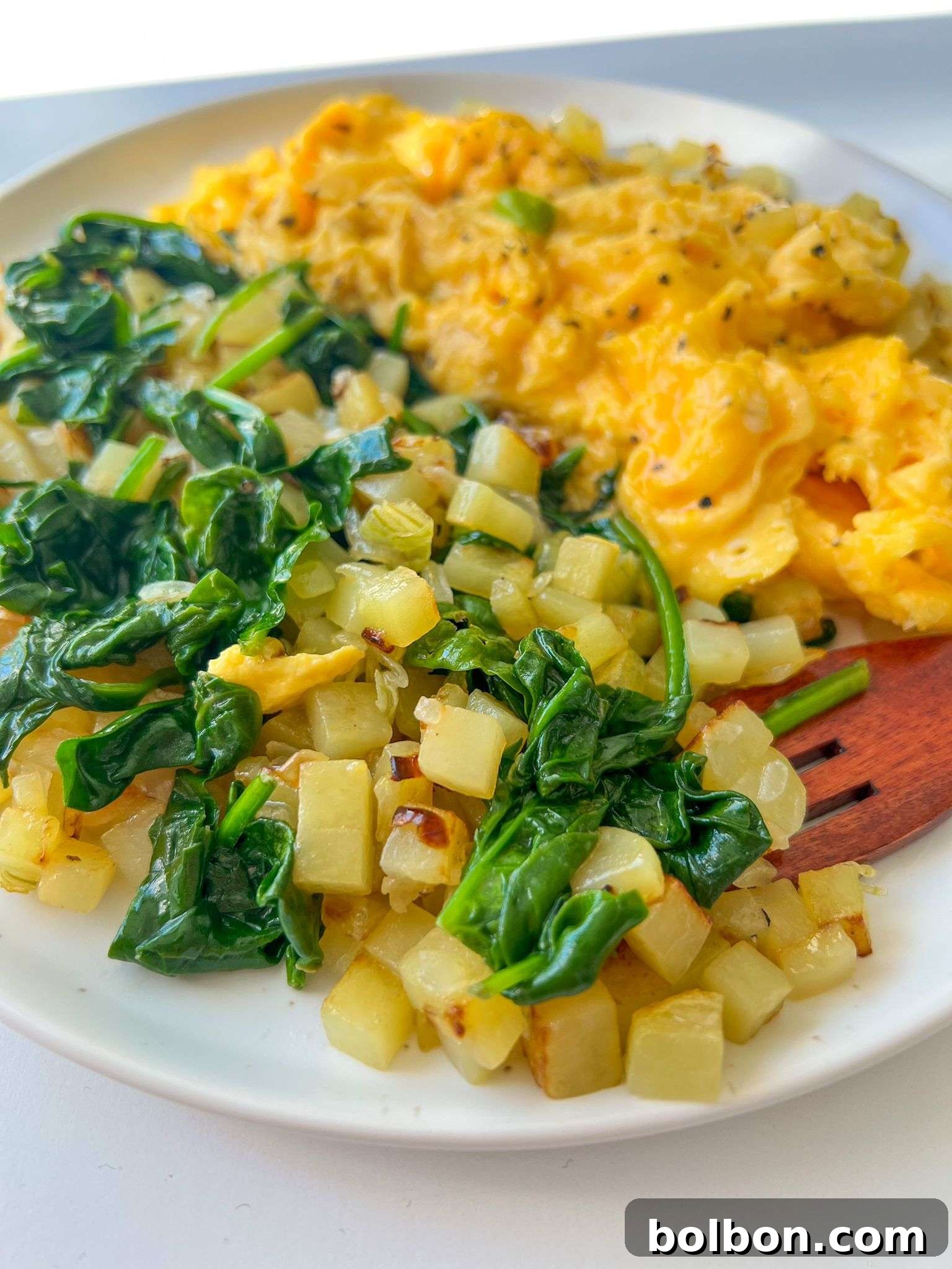 A vibrant plate of Easy Potato Hash with Spinach and Eggs, featuring golden-brown diced potatoes, wilted green spinach, and fluffy scrambled eggs, ready to be enjoyed for a delicious and wholesome breakfast.