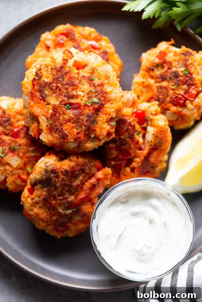 Quick Salmon Cakes 2 A plate of golden brown, crispy fresh salmon patties garnished with a lemon wedge and fresh dill, ready to be served.