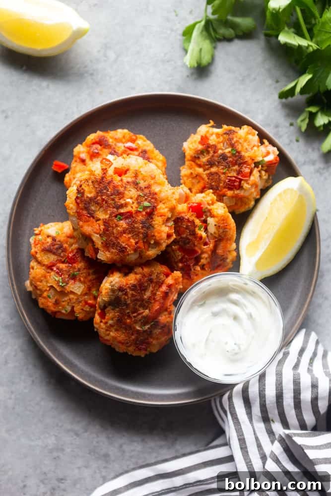 Quick Salmon Cakes 4 A beautiful arrangement of cooked salmon patties on a white serving dish, garnished with fresh herbs and lemon slices.
