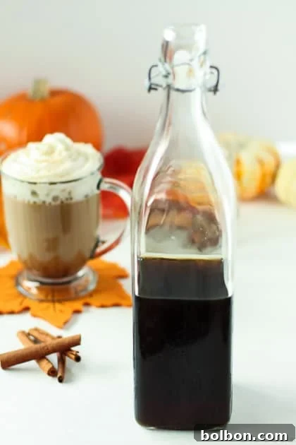 Autumn Spice Syrup latte in a mug, garnished with cinnamon, on a rustic wooden table with fall decorations