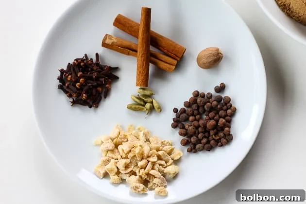 Whole spices for autumn syrup including cinnamon sticks, star anise, cardamom pods, and cloves, laid out on a wooden surface