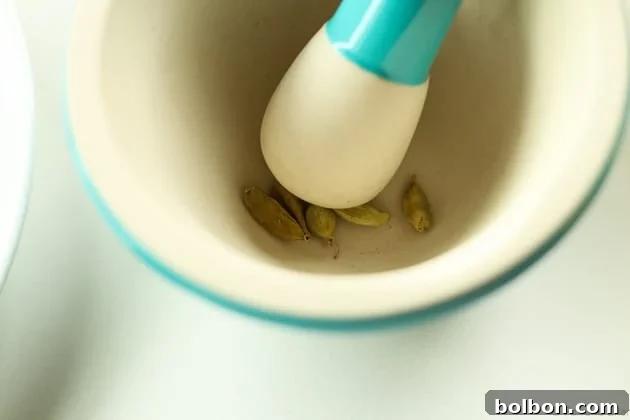 Cardamom pods being crushed in a mortar and pestle, highlighting the aromatic seeds, a key step for the autumn syrup