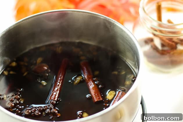 Autumn Spice Syrup being strained through a fine-mesh sieve into a glass jar, separating the spices from the liquid
