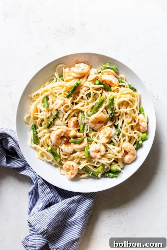 A vibrant bowl of Shrimp and Asparagus Pasta, garnished with fresh herbs and lemon wedges, showcasing succulent shrimp and tender asparagus intertwined with linguine.